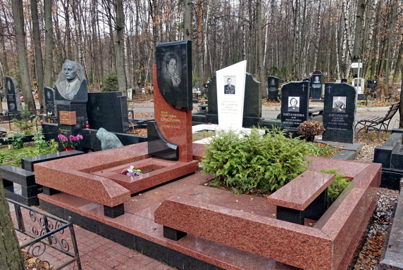 Памятник из двух сортов гранита и карликовая туя в клумбе без бортов